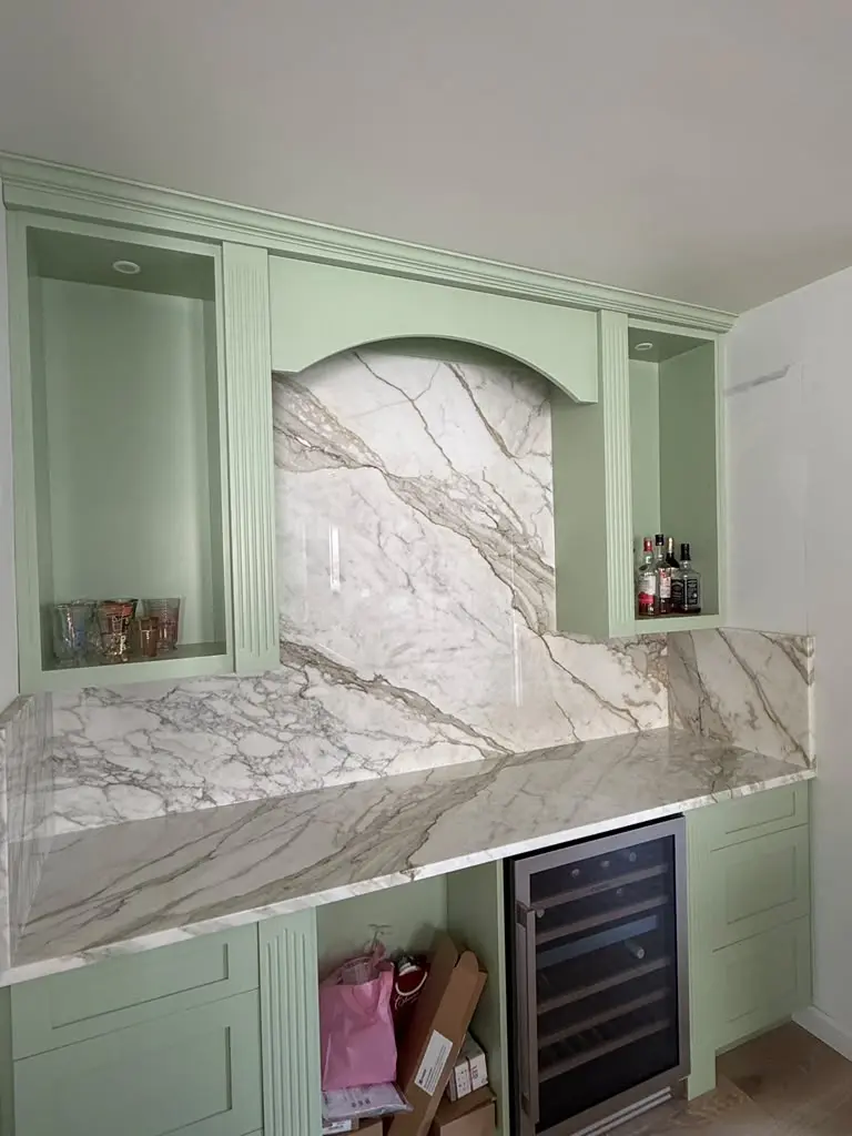 Veined stone backsplash and countertop in a green home bar